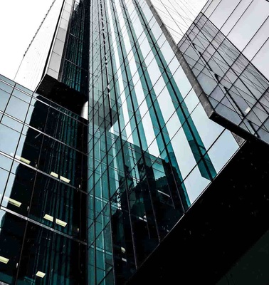 Looking up at a modern glass skyscraper in an urban setting.