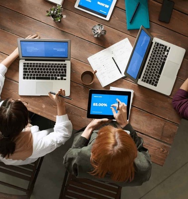 Top view of a diverse group of professionals working together at a desk with laptops and digital tablets.