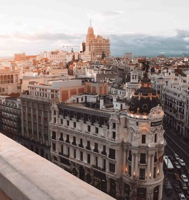 A scenic view of a city at sunset featuring historic architecture and busy streets.