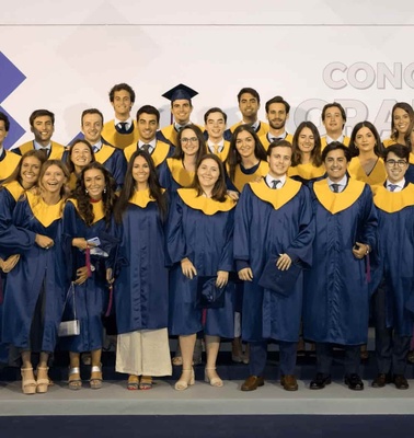 A group of graduates posing in blue and yellow gowns at a graduation ceremony in 2019.