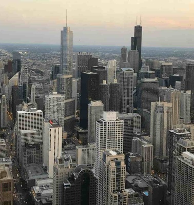 Aerial view of a densely packed urban cityscape with numerous skyscrapers under the evening sky.