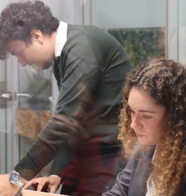 A young man and a young woman are engaged in a discussion inside a modern meeting room.