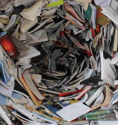 A large pile of mixed papers and magazines, seemingly discarded or ready for recycling.