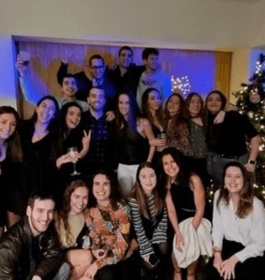 A group of people posing for a photo at a festive indoor event with Christmas decorations in the background.