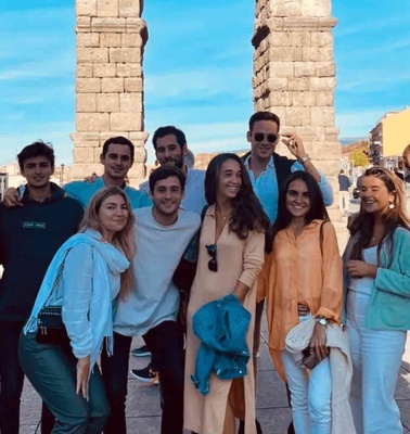 A group of young adults posing for a photo in front of an ancient stone structure with clear blue skies in the background.