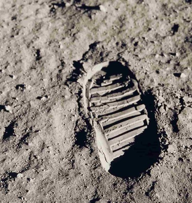 A close-up of a single shoe print embedded in dry, textured soil.