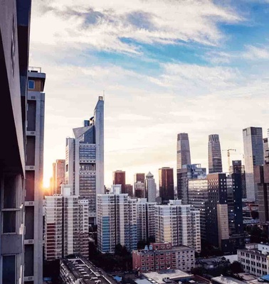 A cityscape at sunrise with modern skyscrapers and residential buildings.