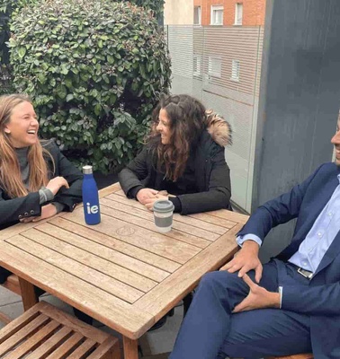 Three people sitting at an outdoor table enjoying a conversation.