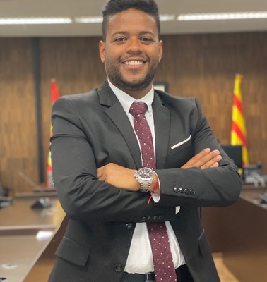 A confident man in a suit standing in a meeting room, smiling at the camera