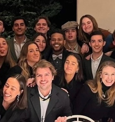 A group of young adults posing together for a photo at a night event.