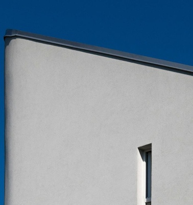 A minimalist building with a sharp corner against a clear blue sky.