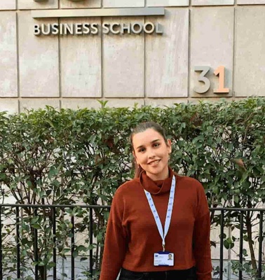 A young woman smiling in front of a Business School building, labeled with the number 31.