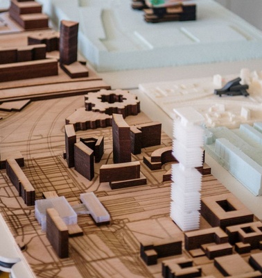 A detailed architectural model displayed on a table, showcasing various buildings and city layout.