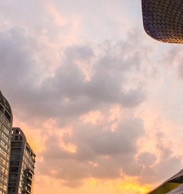 A sunset over a modern cityscape with a uniquely textured building in the foreground.