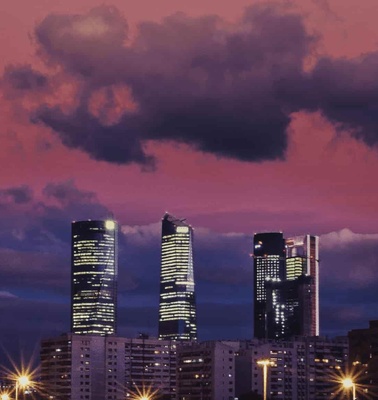 A city skyline at twilight with illuminated skyscrapers under a pink and blue sky.