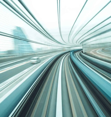 A dynamic motion blur photo of a high-speed train moving through a modern railway.