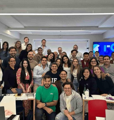 A group of diverse people smiling and posing together in an office or classroom setting.