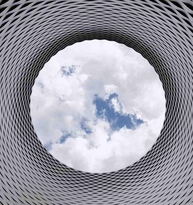 View of the sky through a circular opening surrounded by a geometric pattern structure.