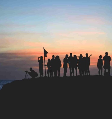 Silhouette of a group of people on a cliff at sunset.