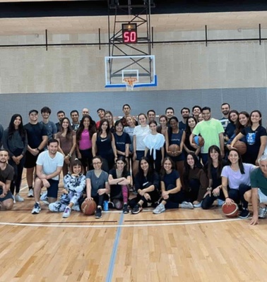 A large group of people posing together in a basketball court.