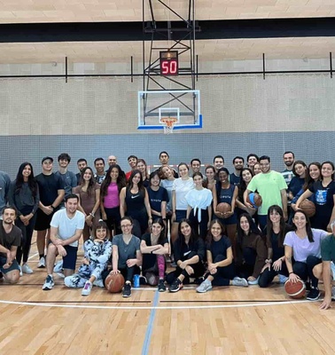 A large group of people posing together in a basketball court.