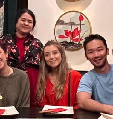 A group of people smiling and posing at a table in a restaurant.