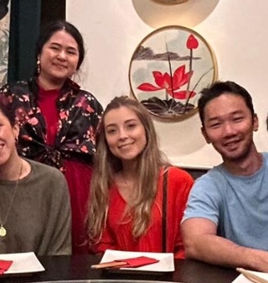 A group of people smiling and posing at a table in a restaurant.