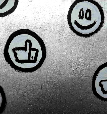 A wall painted with various black and white circular icons, including a smiley face, a heart, and thumbs up symbols.