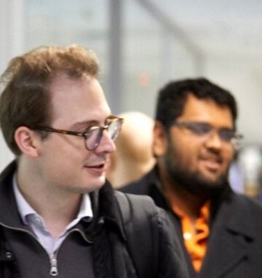 Four men walking and chatting in an office corridor.