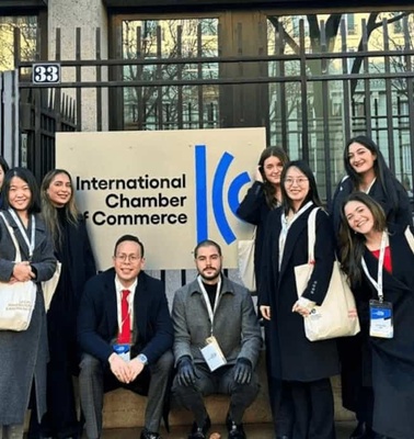 A group of nine people posing in front of the International Chamber of Commerce sign.