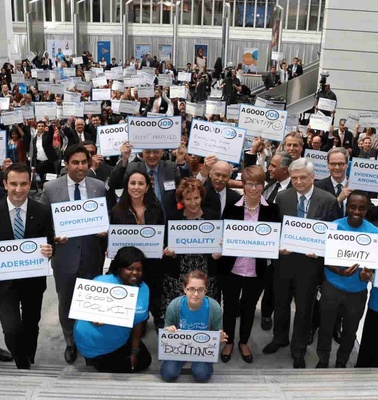 A group of diverse people holding signs with messages about leadership, equality, and education in a large indoor space.