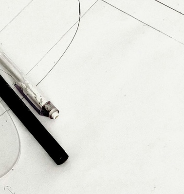 An arrangement of a pen, a ruler, and a drawing template on a blank sheet of paper.