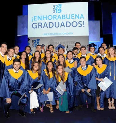 A group of graduates in blue and gold robes celebrating at their graduation ceremony.