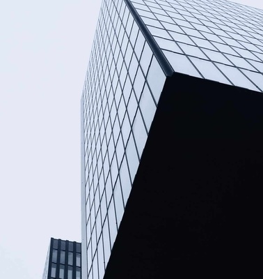 Low angle view of a modern skyscraper with a geometric glass facade against a clear sky.