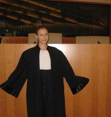 A woman in a judicial robe stands confidently in a courtroom.