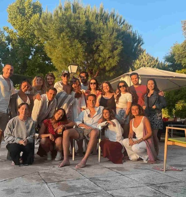 A group of people posing together outdoors during sunset with trees and a patio setting in the background.