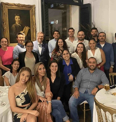 A group of people posing for a photo during a gathering in a dining room with paintings and elegant decor.