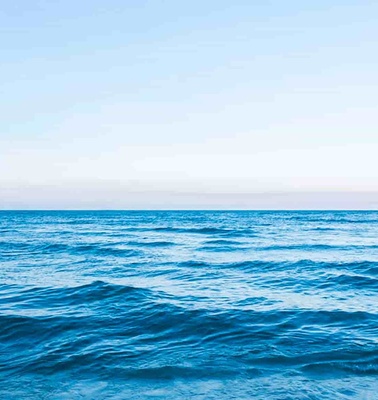 A serene view of the ocean with gentle waves under a clear blue sky.