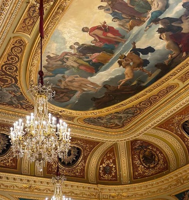 A grand interior featuring ornate chandeliers and a painted ceiling.