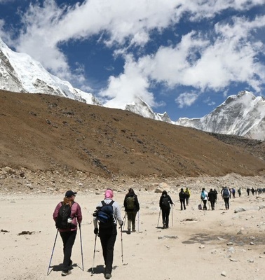 A group of hikers traversing a mountainous terrain under a blue sky.
