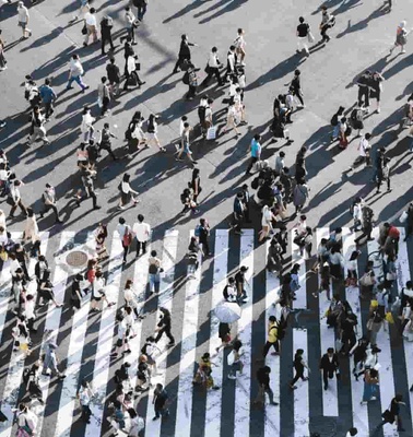 Aerial view of numerous people crossing a large zebra crossing in an urban area.