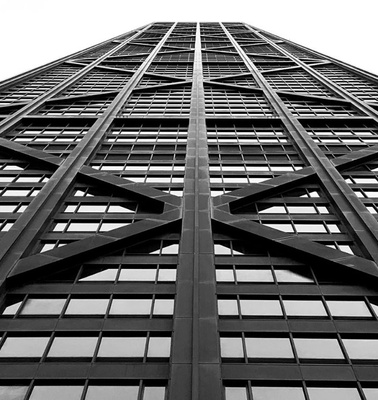 The image showcases a tall, modern building viewed from a low angle, highlighting its sleek design and structural patterns.
