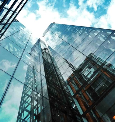 Low-angle view of modern glass skyscrapers under a clear blue sky.
