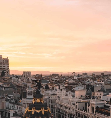 A sunset view over a sprawling city skyline with notable buildings and warm sky hues