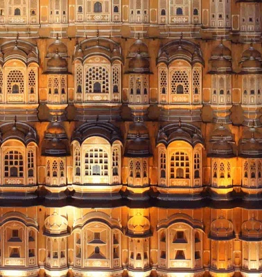 Illuminated facade of a grand traditional Indian palace with intricate architectural details.