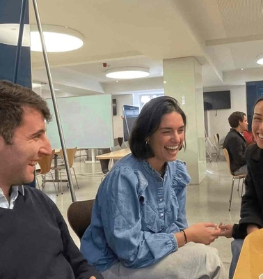 Three people sitting at a table in a modern cafe, laughing and conversing.