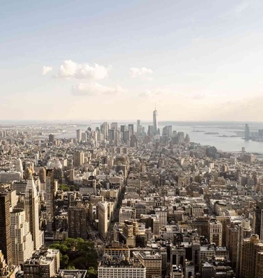 Aerial view of a densely populated cityscape with modern skyscrapers and a large river visible in the background.