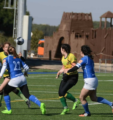 Women athletes playing soccer, competing intensely for the ball on a sunny day.
