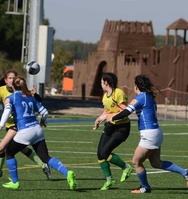 Women athletes playing soccer, competing intensely for the ball on a sunny day.