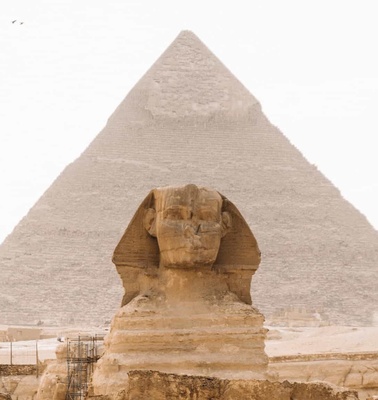 A photograph of the Great Sphinx with the Pyramid of Khafre in the background under a clear sky.